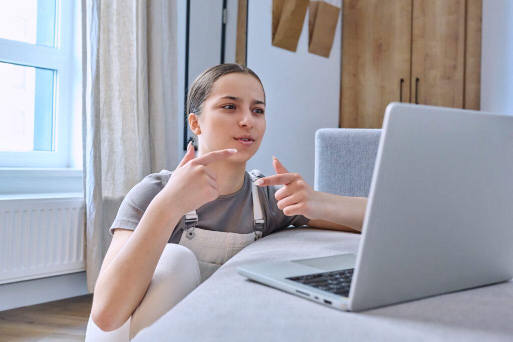 Woman sitting at laptop attending an online person-centred therapy session.